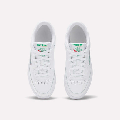 The Women's Club C 85 Shoes by Reebok are white sneakers with green Reebok logos and tongue detailing, a clean minimalist look, and toe perforations, shown from an overhead view.