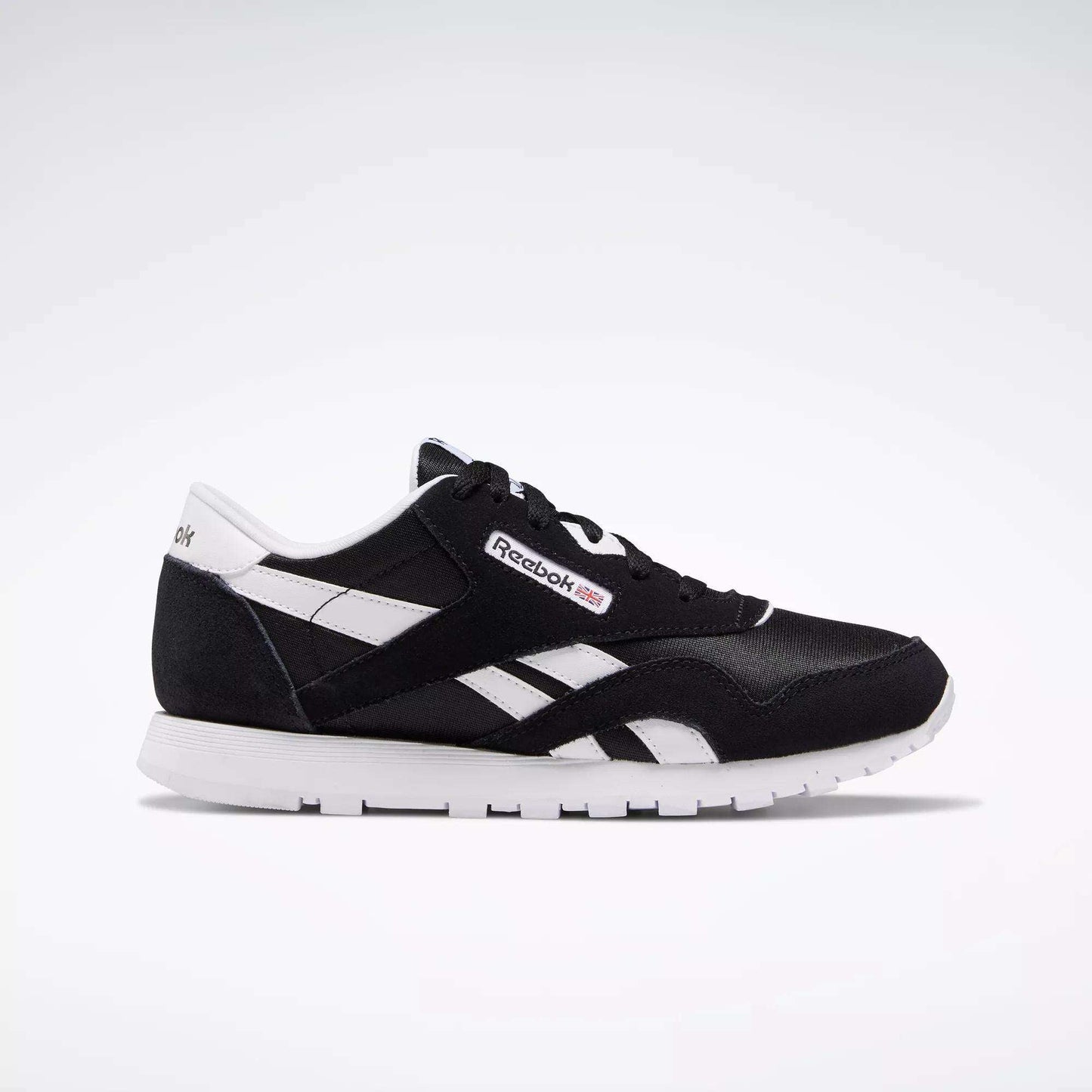 The Reebok Classic Nylon Shoes - Big Kids are displayed in black and white from a side angle on a white background, showcasing the iconic Reebok logo, white stripes, and sole—ideal for those who love minimalist style.