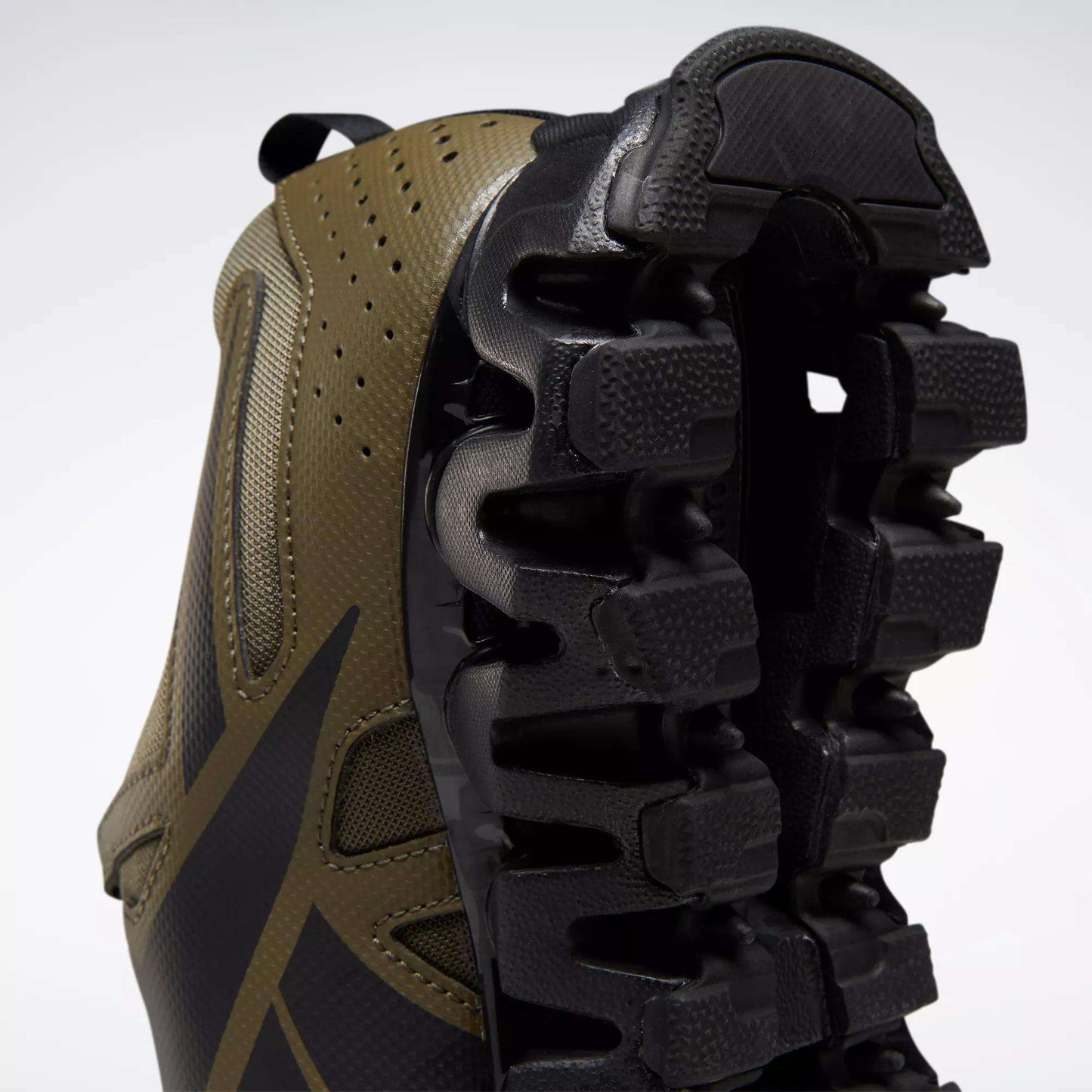 Close-up of the Reebok Men's ZigWild Trail 6 Shoes, showcasing a brown and black design with a chunky, trail-inspired black sole featuring enhanced cushioning and deep grooves, set against a plain white background.