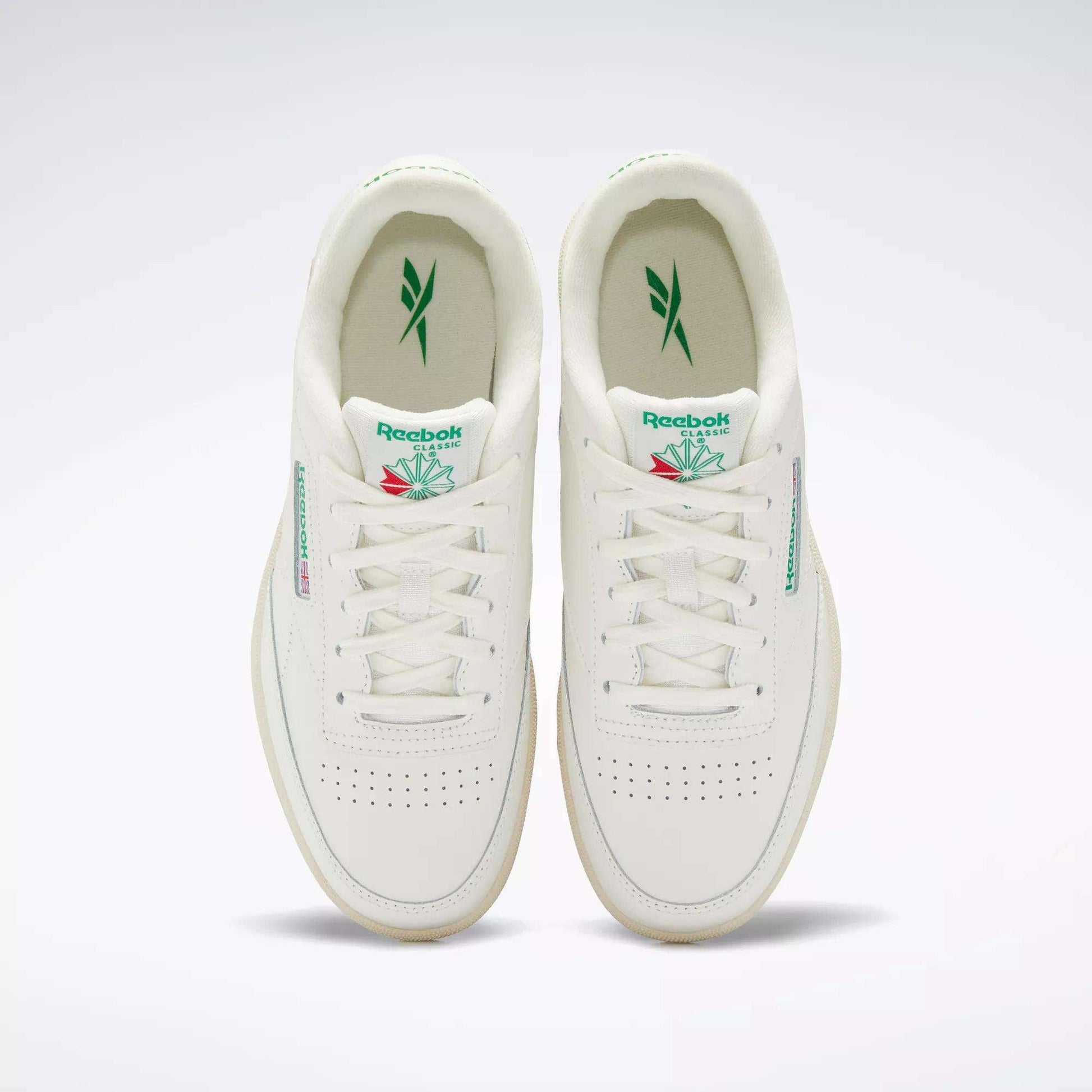 The Reebok Club C Shoes for big kids are white sneakers with green accents, featuring the Reebok logo on the tongue and side, plus perforated toe boxes for classic '80s style.