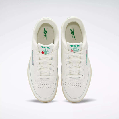 The Reebok Club C Shoes for big kids are white sneakers with green accents, featuring the Reebok logo on the tongue and side, plus perforated toe boxes for classic '80s style.