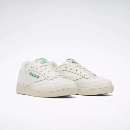 The Reebok Kids' Club C Shoes - Preschool, seen at an angle on a white background, feature off-white uppers with green and red logo accents, capturing classic '80s style for a timeless, retro-inspired look.