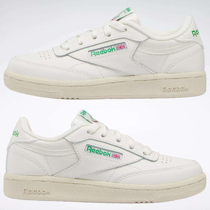 Two white Reebok Kids' Club C Shoes - Preschool, shown from the side with green and red logo details and an off-white sole, bring timeless '80s style for everyday wear.