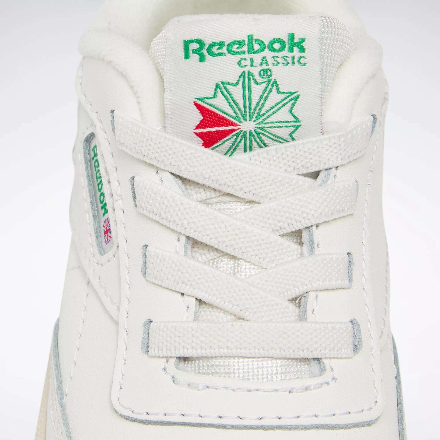Close-up of Reebok Kids' Club C Shoes for babies and toddlers, featuring '80s-inspired details like the green and red tongue logo, white laces, and side label with the Reebok name and Union Jack flag—ideal for classic sneaker fans.