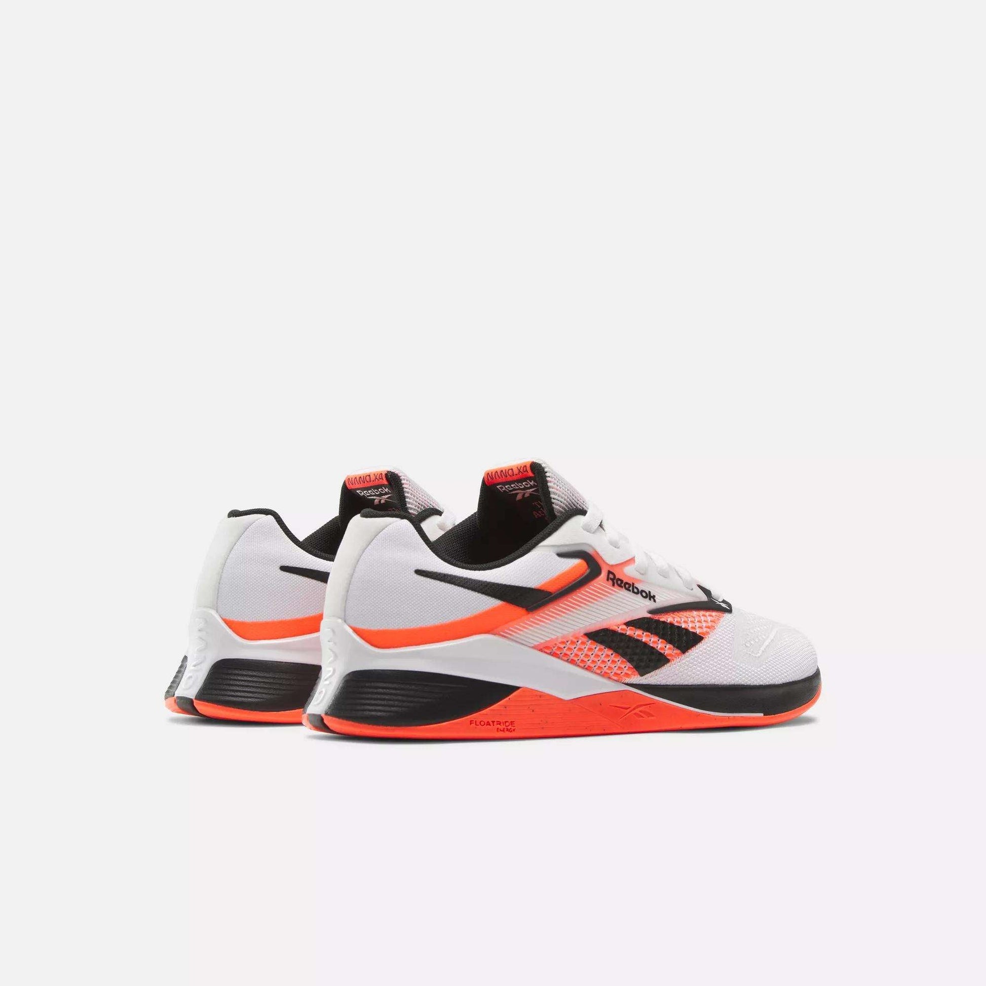 The Reebok Women's Nano X4 Training Shoes in white, black, and orange, shown on a plain white background, feature a breathable mesh design and visible Reebok logos on the sides.