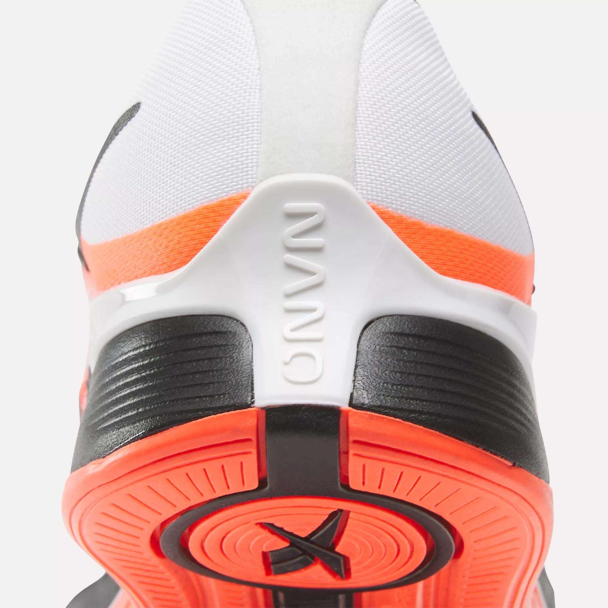 Close-up of the back of a white, black, and orange Reebok Women's Nano X4 Training Shoe shows the heel, textured sole, and embossed NANO on the heel tab. Enjoy superior support with these lightweight training shoes.