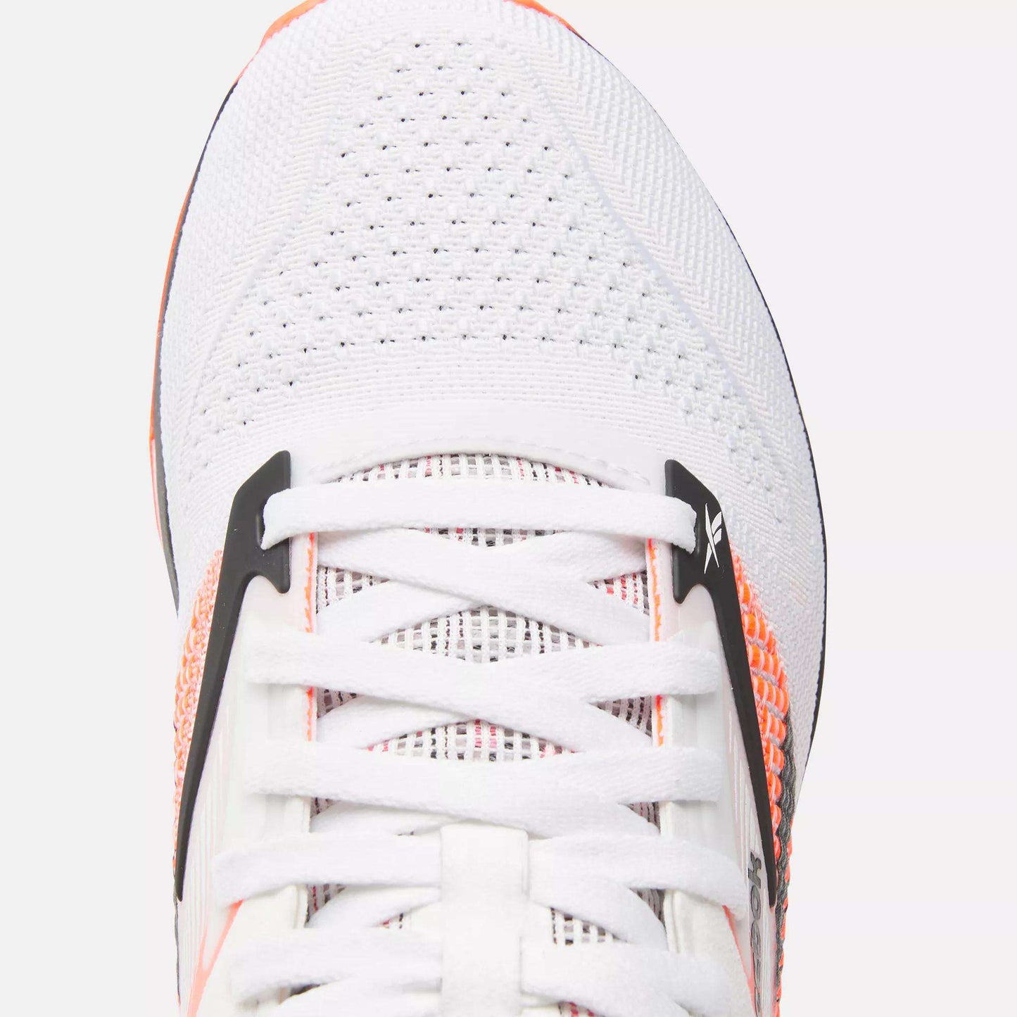 Close-up of Reebok Women's Nano X4 Training Shoes in white with orange accents and black details, featuring white laces and breathable mesh—ideal for those seeking lightweight training footwear.