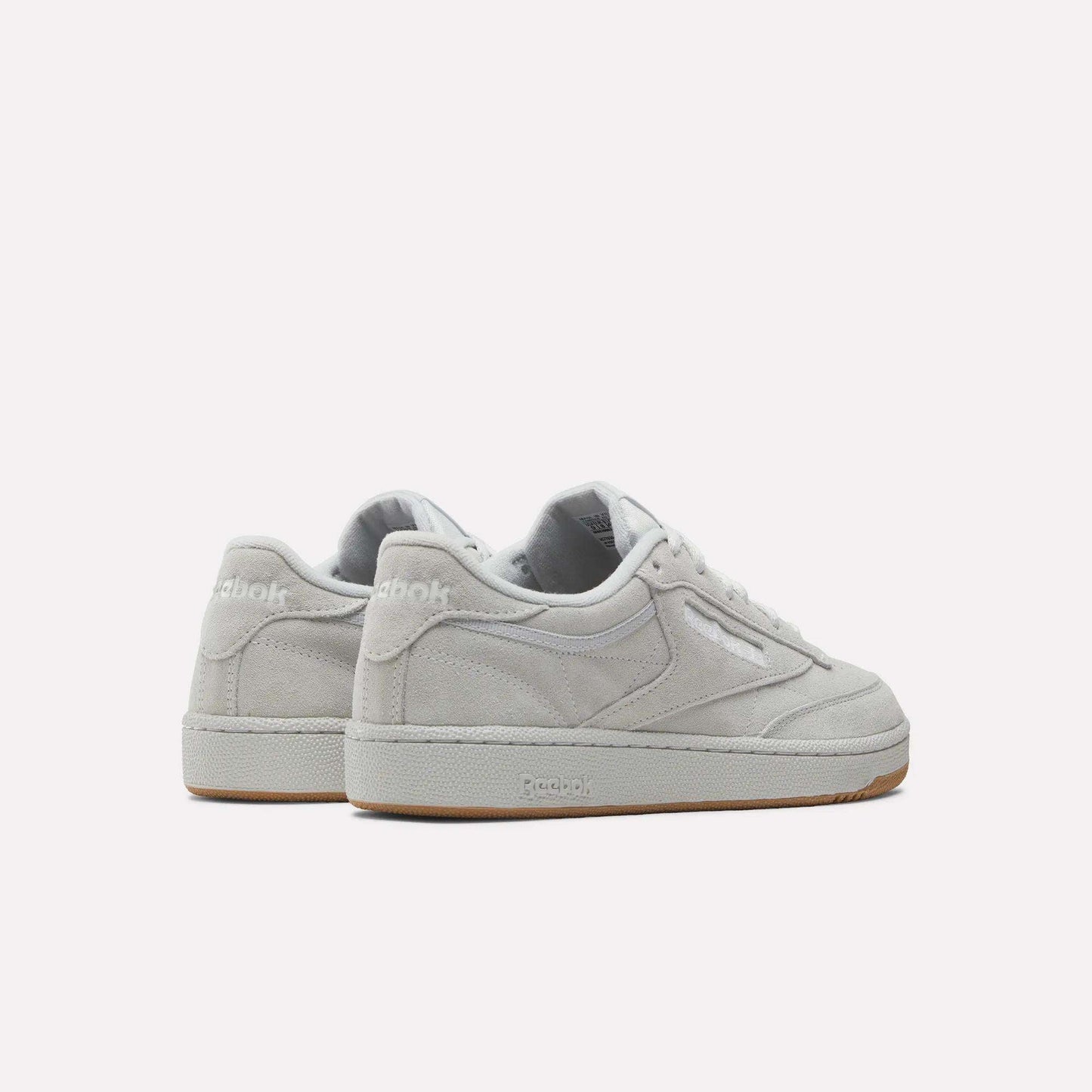 The Reebok Club C 85 Shoes feature a light gray suede upper, white laces, and beige rubber soles, displayed from an angled back and side view against a plain white background.
