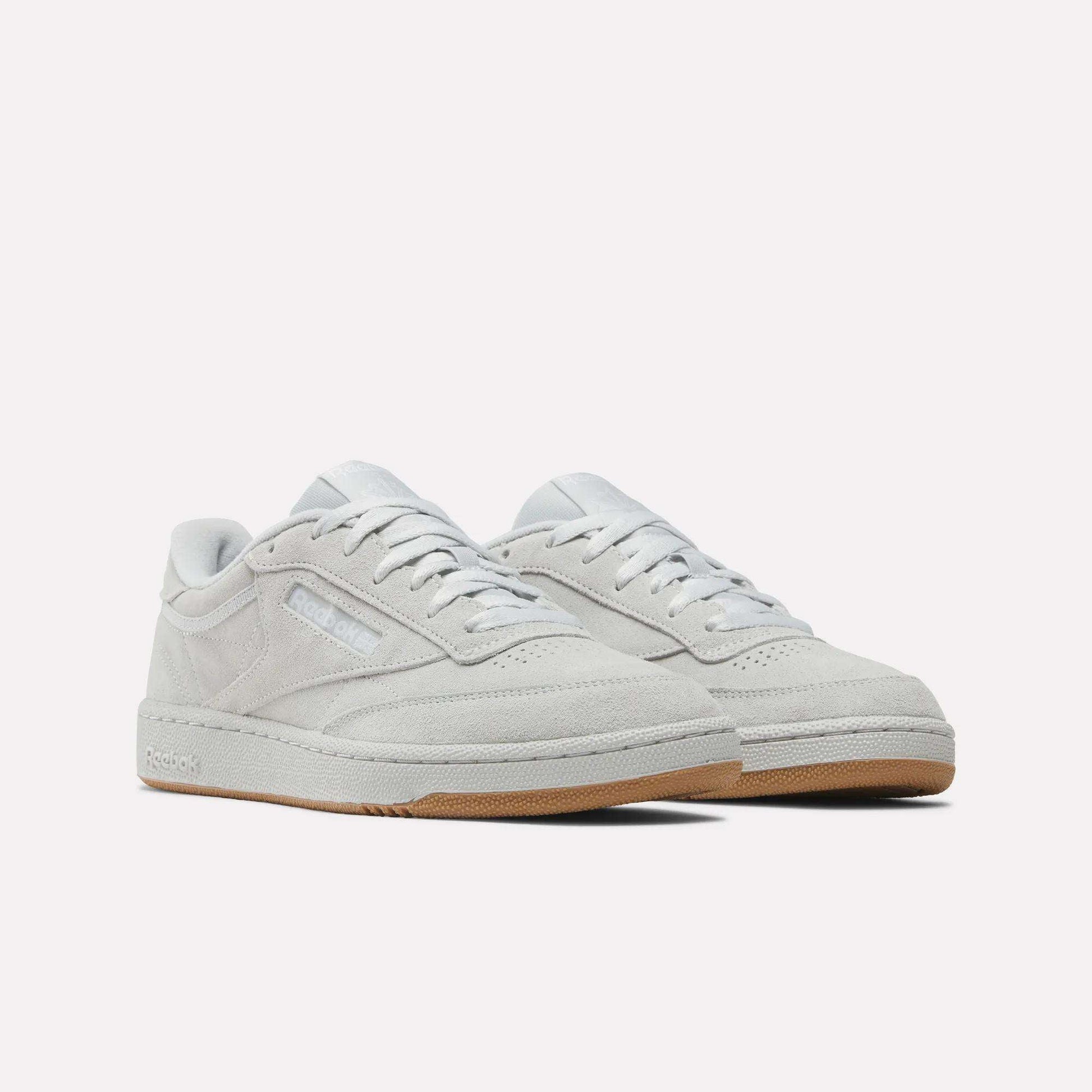 The Reebok Club C 85 Shoes feature a light gray suede upper, white laces, and gum rubber outsoles for a classic court look, highlighted against a plain white background.