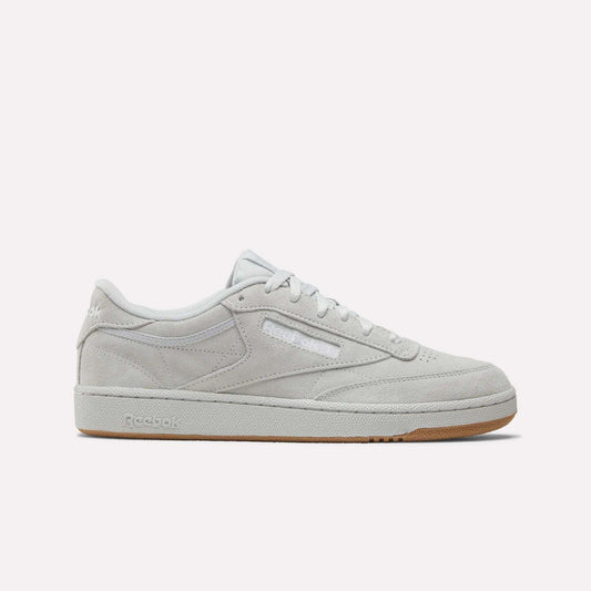 A side view of the Reebok Club C 85 Shoes in light grey suede with white laces, a slightly off-white sole, and a light brown gum bottom. The Reebok logo is displayed on the side and heel.