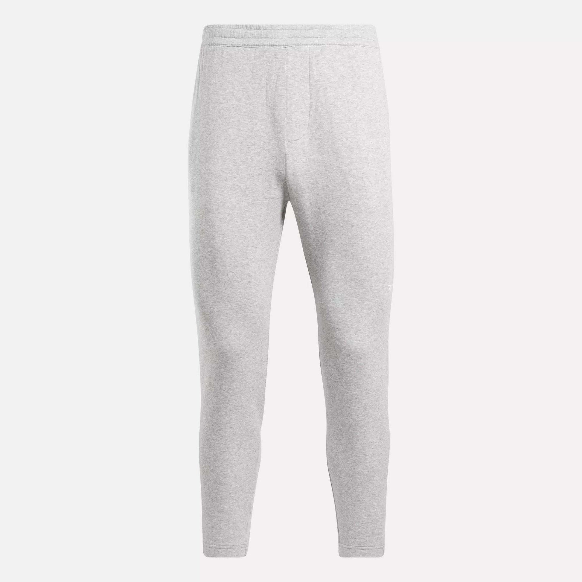 The Reebok Men's Active Collective DreamBlend Pants in light gray feature a slim, tapered leg, soft DreamBlend fabric, and an elastic waistband, shown here on a plain white background.