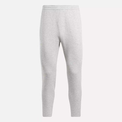 The Reebok Men's Active Collective DreamBlend Pants in light gray feature a slim, tapered leg, soft DreamBlend fabric, and an elastic waistband, shown here on a plain white background.