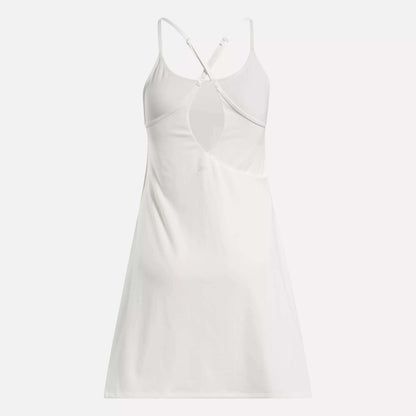 The Reebok Women's Lux Strappy Dress is a sporty, sleeveless white dress with thin crisscross adjustable back straps and a keyhole cutout below the shoulder blades, shown on a plain white background.