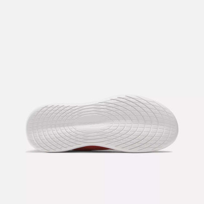 The image shows the bottom view of a Women's Active Lite Shoe sole by Reebok, featuring a textured wavy grip pattern. The Reebok name is embossed at the center. The minimalist sneaker is set against a plain, light-colored background.