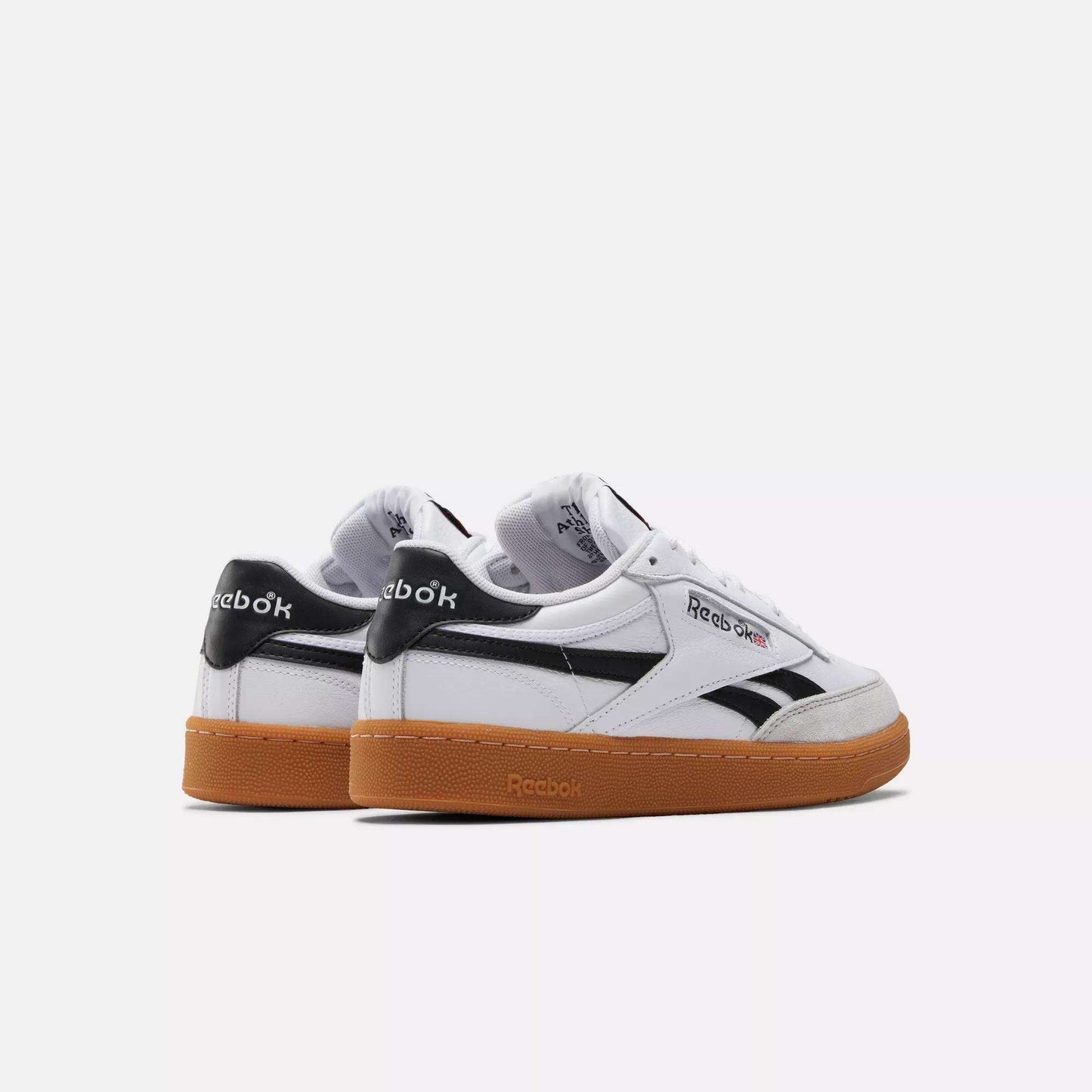 Two white Reebok Men's Club C Revenge Vintage Shoes with black accents and gum soles are displayed side by side on a white background. The classic Reebok logo appears on the side and heel, highlighting these timeless casual sneakers.