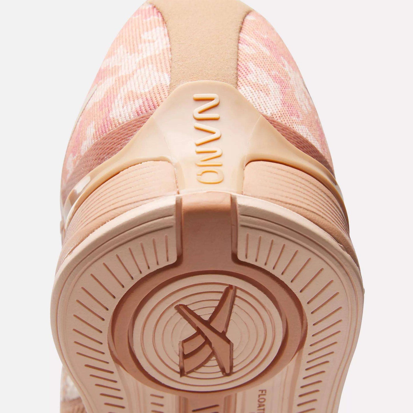 Close-up of the heel and sole of Reebok Women's Nano X4 Training Shoes in pink with beige accents. "NANO" appears on the heel, and the lightweight, breathable sole features circular patterns with an X design at the center.