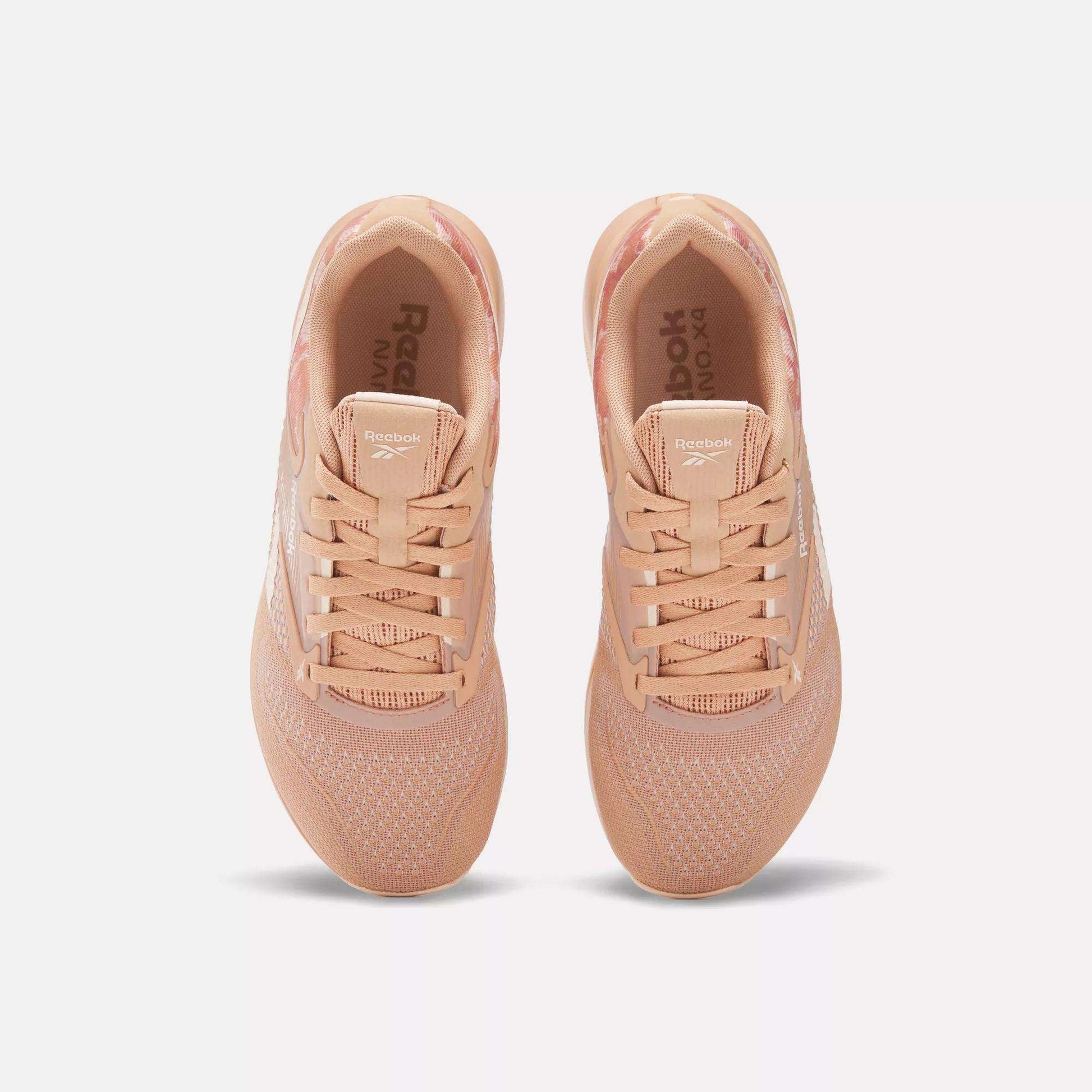 A pair of Women's Nano X4 Training Shoes by Reebok in peach, shown from above with breathable mesh uppers, laces, and white Reebok branding on the sides. The lightweight sneakers are side by side on a plain white background.