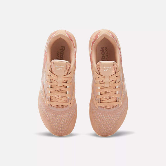 A pair of Women's Nano X4 Training Shoes by Reebok in peach, shown from above with breathable mesh uppers, laces, and white Reebok branding on the sides. The lightweight sneakers are side by side on a plain white background.