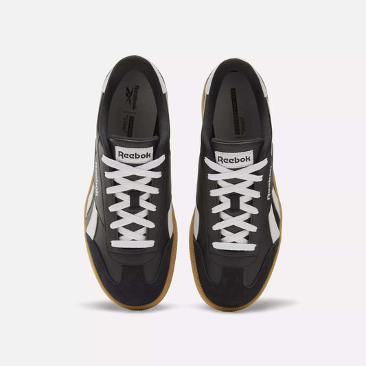 Top view of Reebok Smash Edge Shoes in black, featuring white laces, white side stripes, and brown rubber soles. These minimalist sneakers are positioned side by side on a plain white background.