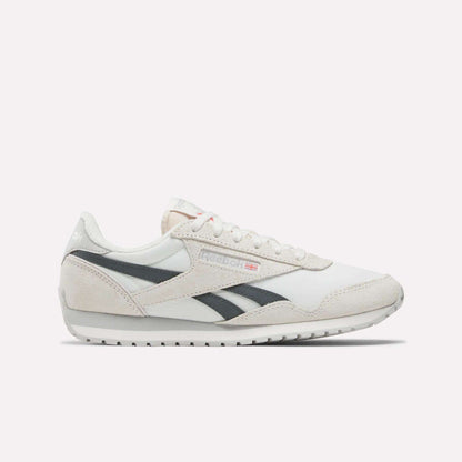 Side view of Reebok Women's Classic AZ Shoes in white with light gray suede accents, black stripes, flat rubber sole, plus Reebok logo and small Union Jack on the side.