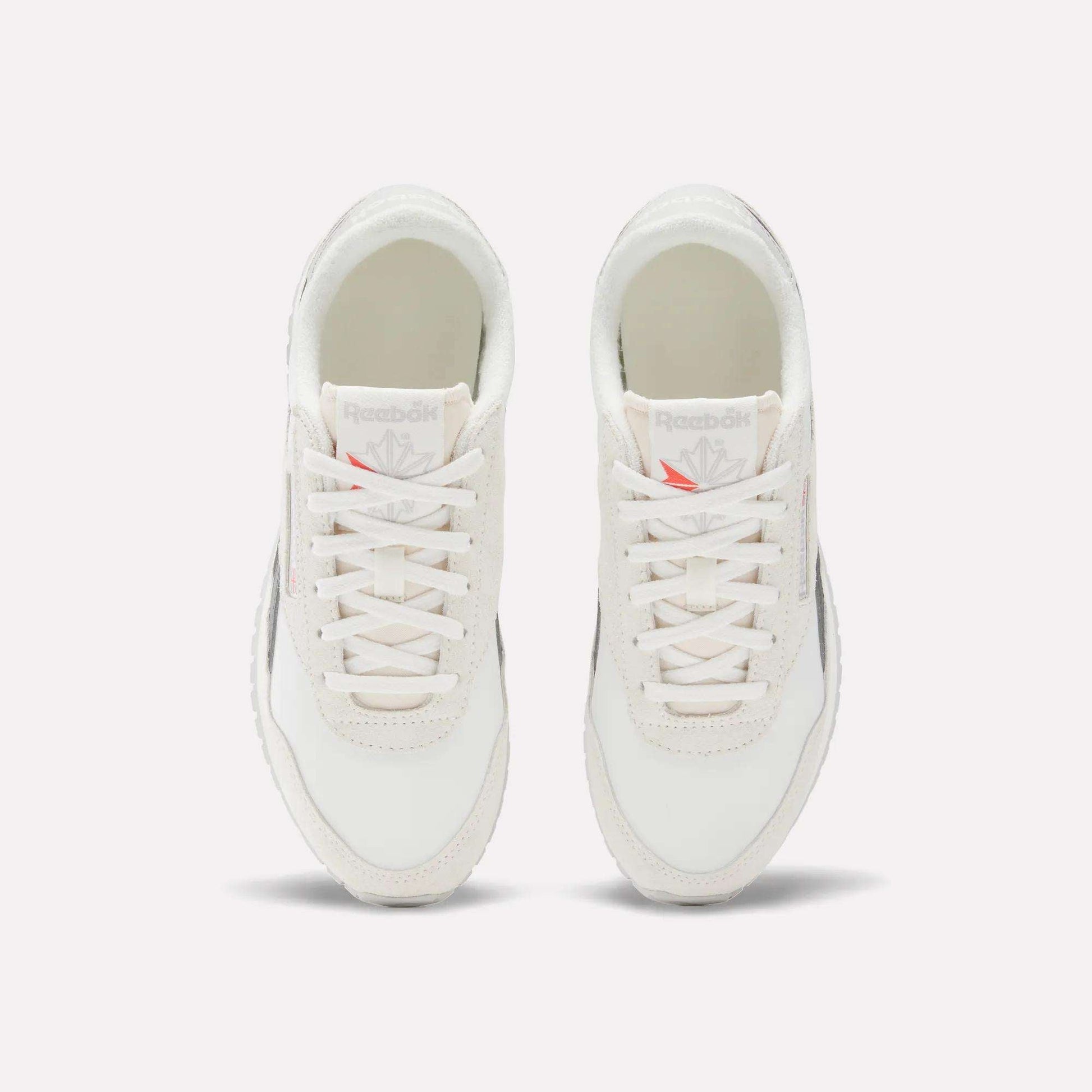 A pair of Reebok Women's Classic AZ Shoes is shown from above, featuring white laces, light grey suede accents, and Reebok logos on the tongues. The running shoes are placed side by side on a white background.
