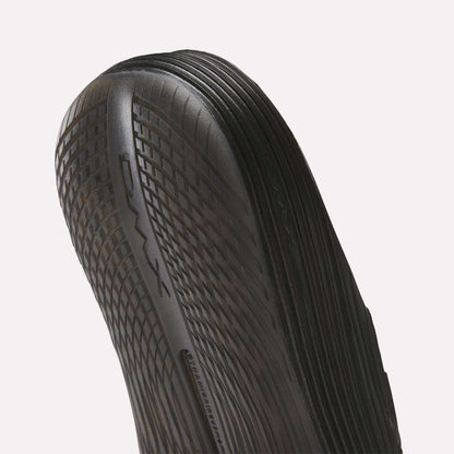 Close-up of the black, textured sole on Reebok DMX Recovery Walking Slides, showing DMX moving air cushioning along the side and detailed ridged patterns for enhanced grip.