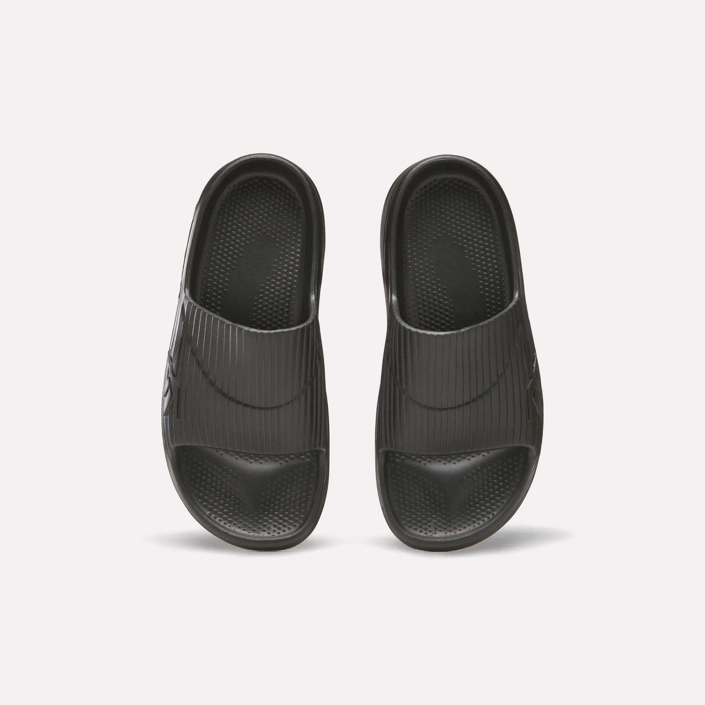 Reebok DMX Recovery Walking Slides in black, shown from above on a white background; feature wide ribbed straps, textured footbeds, and ultra-soft foam for comfort.
