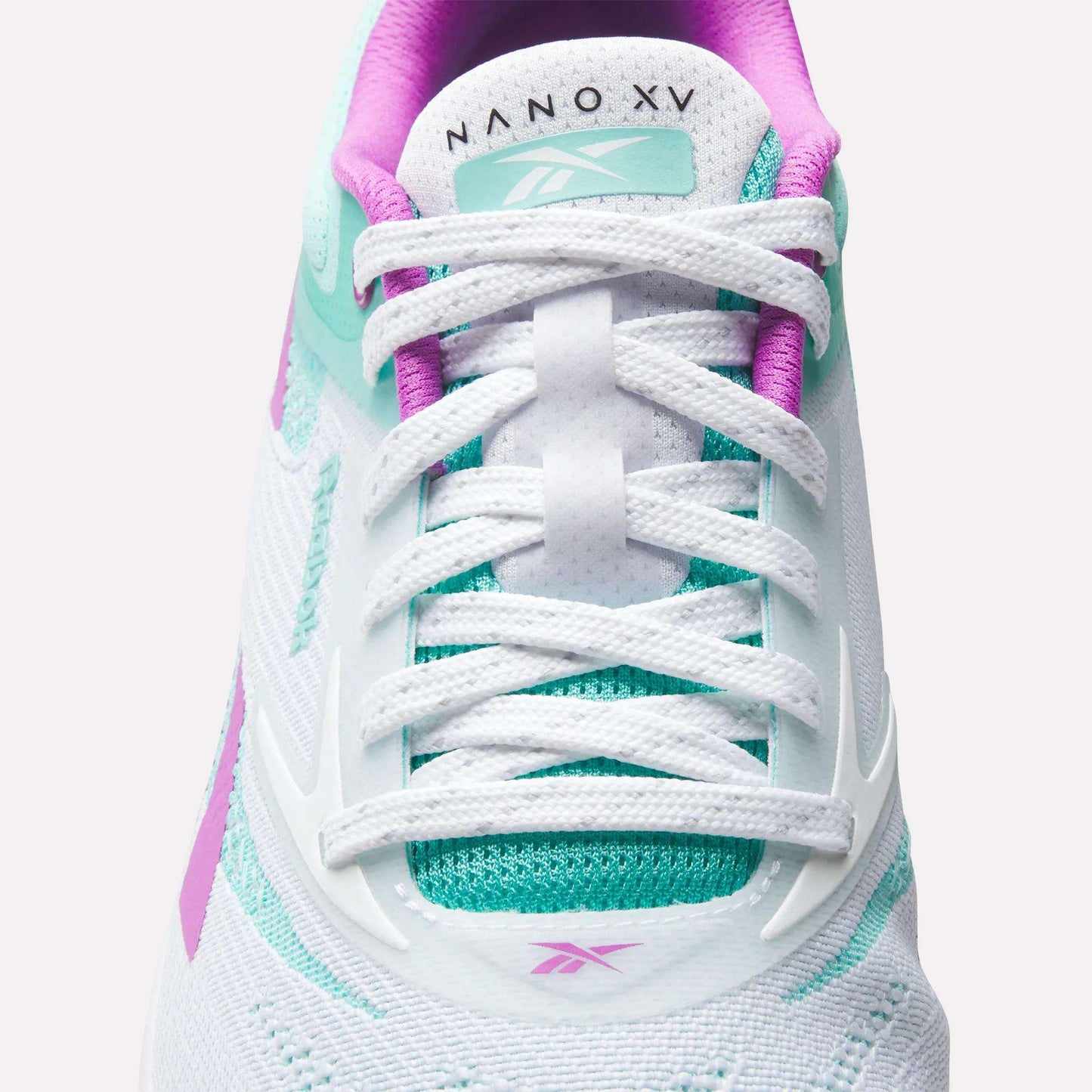 Close-up of a white Reebok Nano X5 Training Shoe with teal and purple accents, white laces, and "NANO X5" text on the tongue. Features mesh and synthetic details for men's training support.