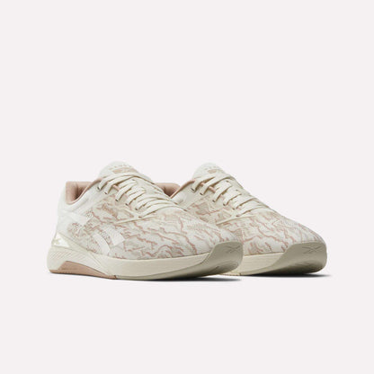 The Reebok Nano X5 men's training shoes feature a beige, patterned textured upper with light brown accents, displayed against a plain white background.