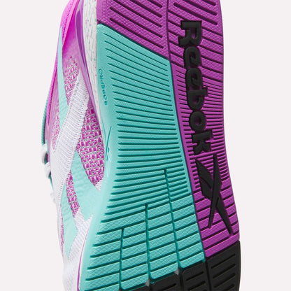 Close-up of the sole of Reebok Women's Nano X5 Training Shoes, showing textured grip patterns in pink, teal, and black, with the “Reebok” name and logo clearly visible.