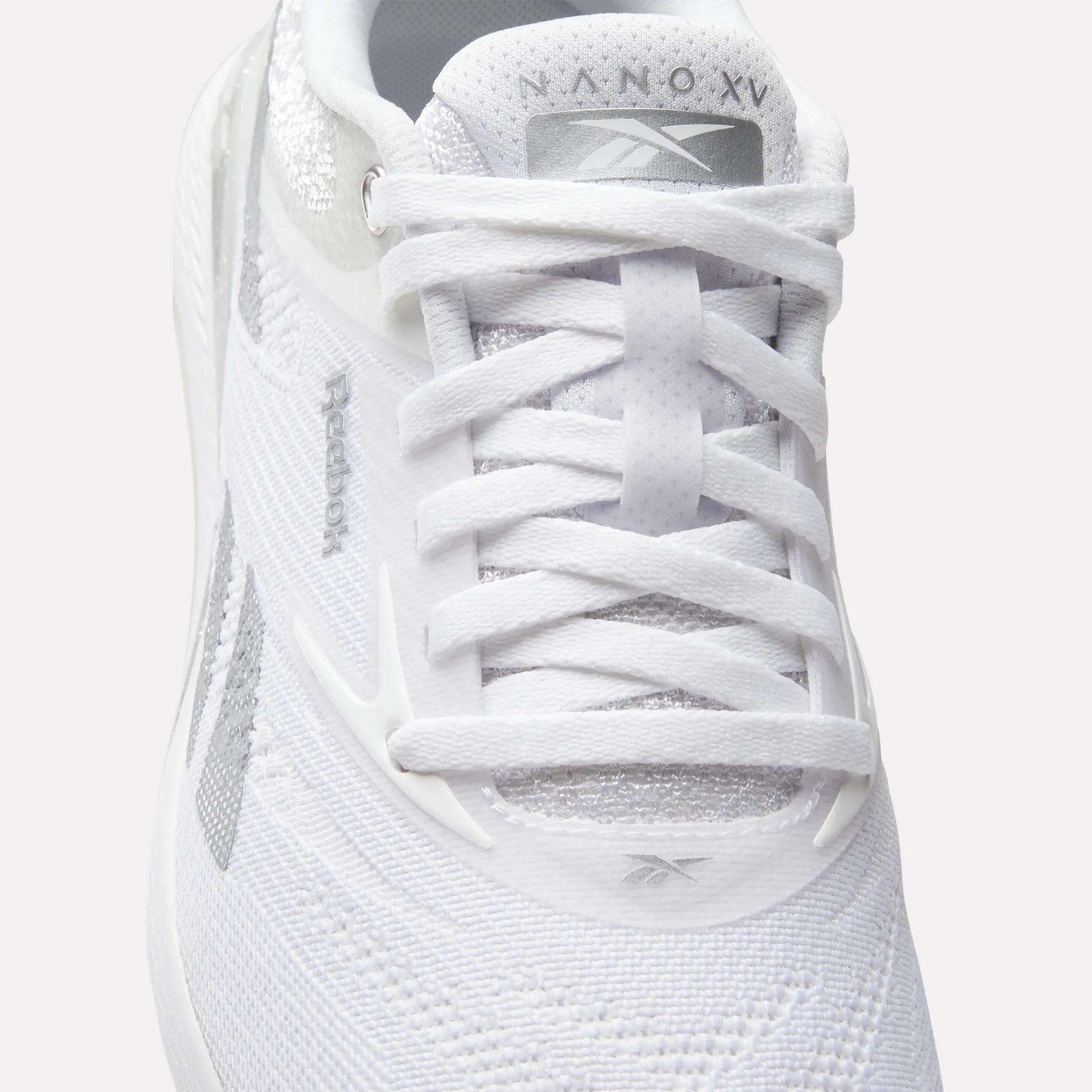 Close-up of a white Reebok Women's Nano X5 Training Shoe viewed from above, featuring visible laces, the Reebok logo on the tongue, mesh fabric details, and branding that highlights these comfortable training shoes.