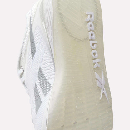 Close-up of the sole of Reebok Women's Nano X5 Training Shoes, highlighting the Reebok logo and textured grip on the transparent sole. The upper features a subtle gray design for style and comfort.
