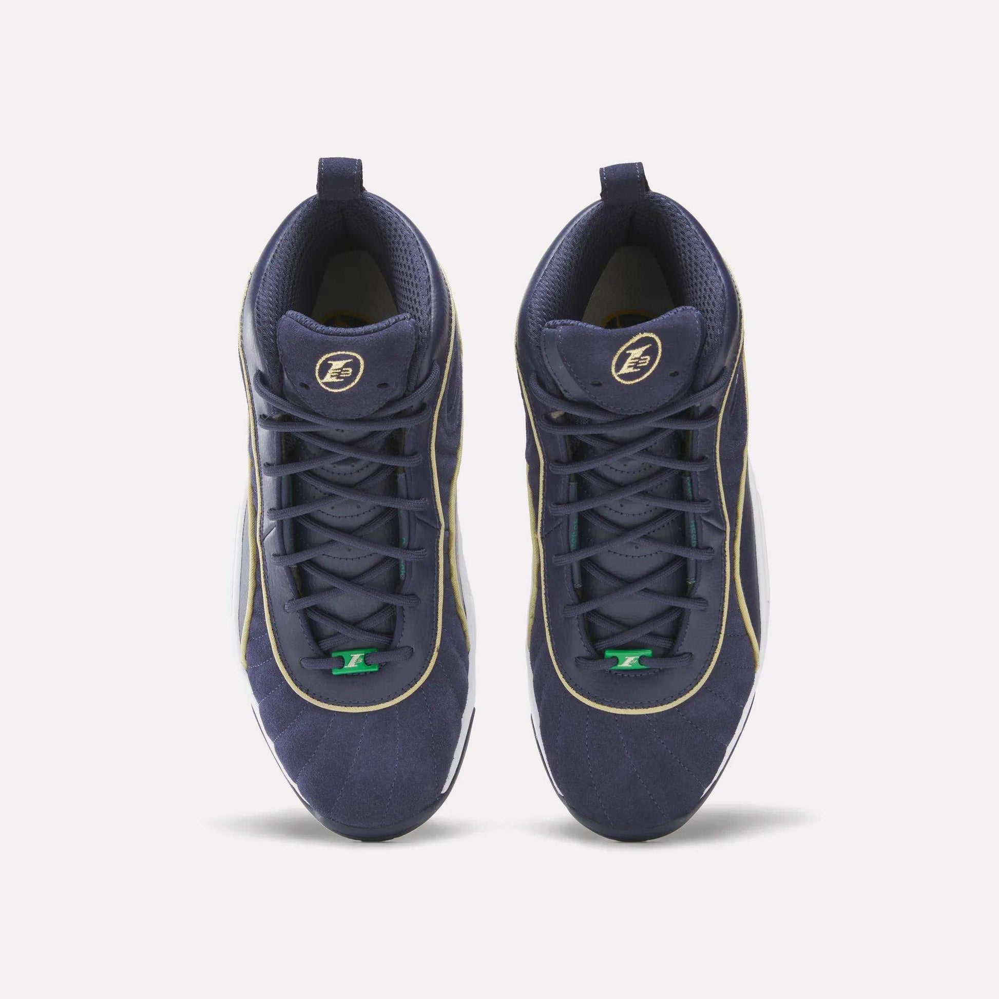 A pair of Reebok Answer III Shoes in navy blue with gold trim, green lace accents, and a circular logo on each tongue are symmetrically arranged on a plain white background, showcasing their retro basketball style.