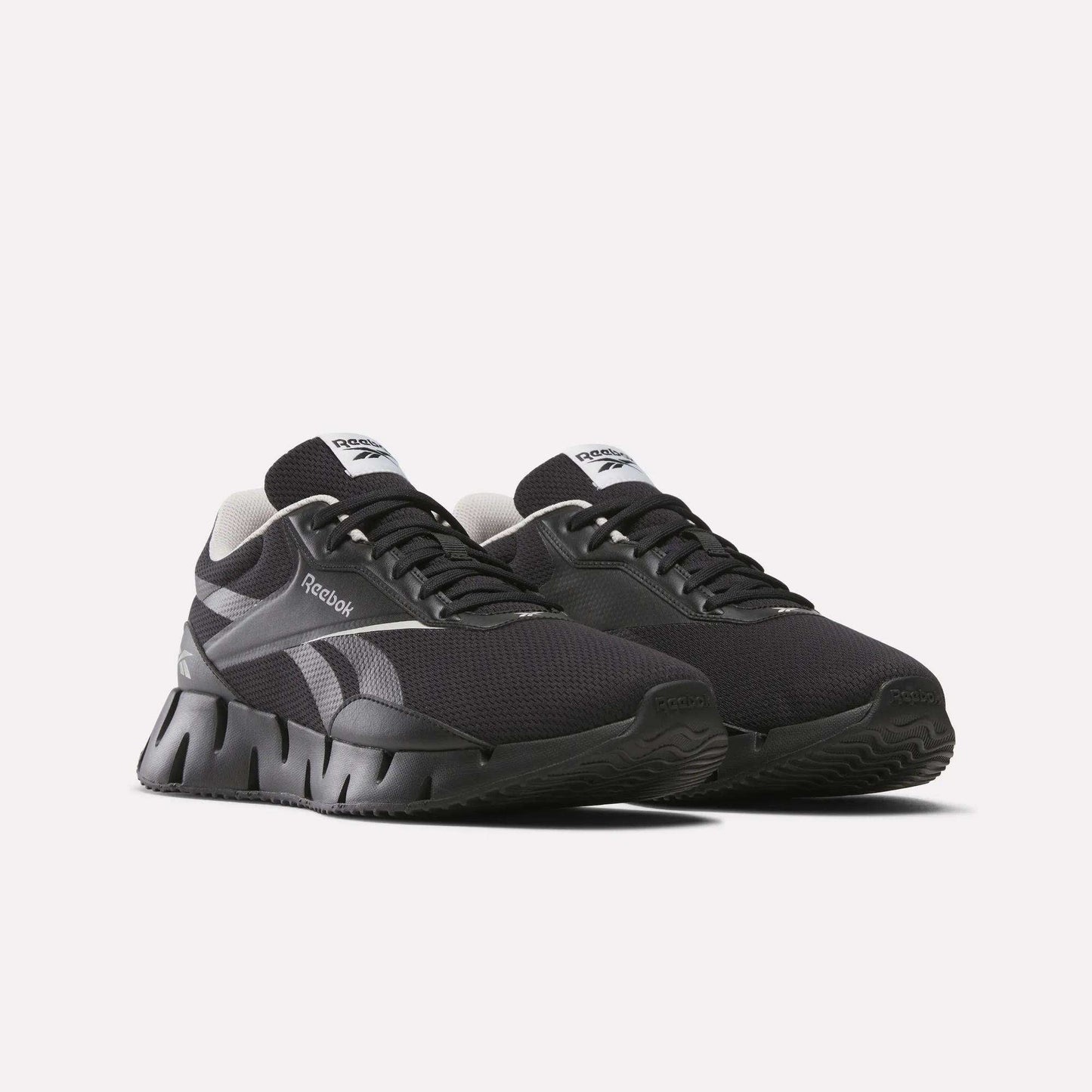 A pair of black Reebok Zig Dynamica STR running shoes with white accents, FuelFoam midsole, thick segmented soles, and mesh uppers is displayed against a plain white background.