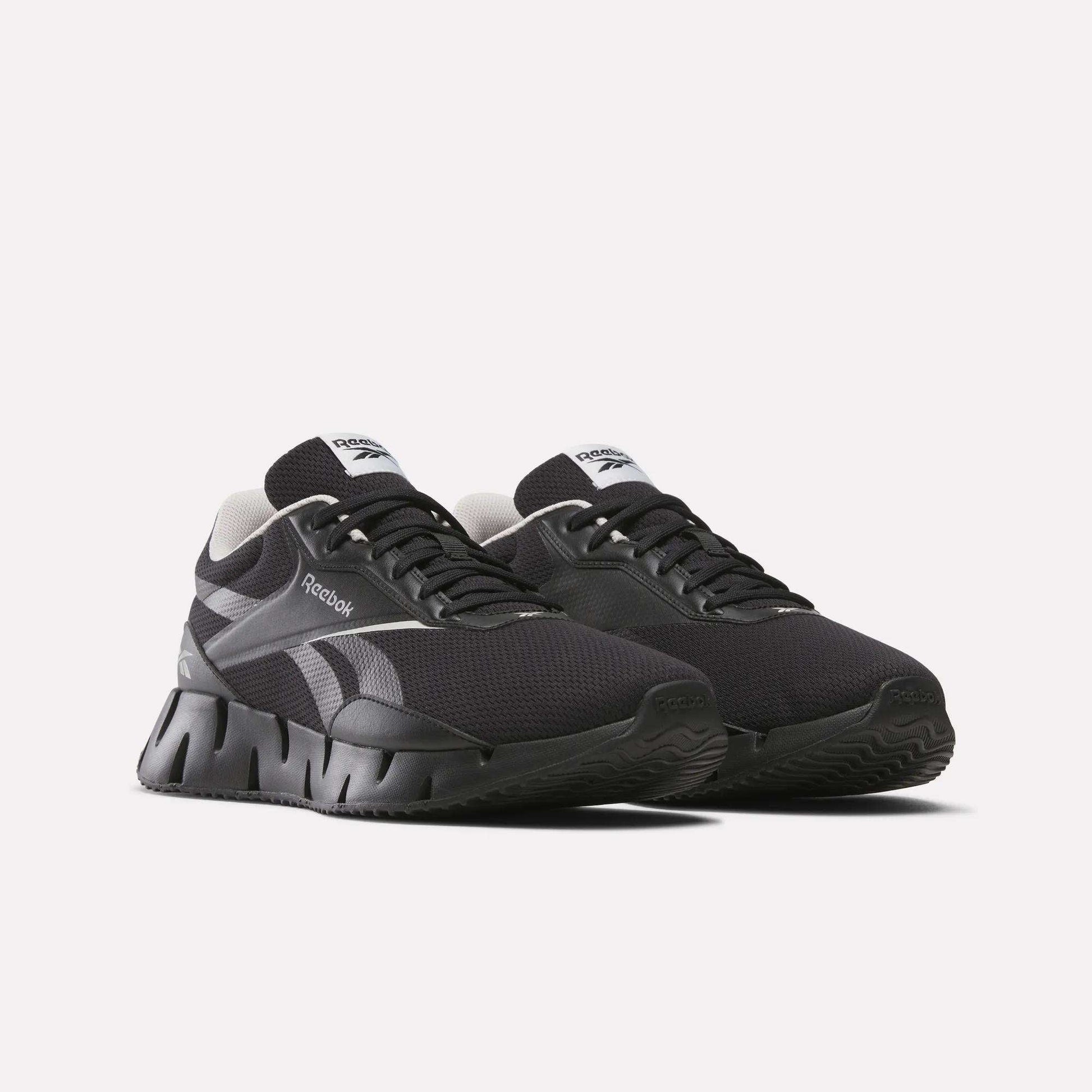 A pair of black Reebok Zig Dynamica STR running shoes with white accents, FuelFoam midsole, thick segmented soles, and mesh uppers is displayed against a plain white background.