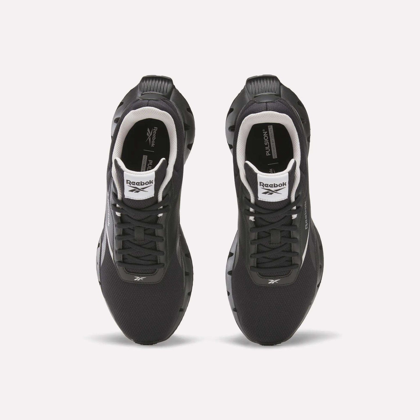 Top view of a pair of black Reebok Zig Dynamica STR Shoes with white accents, black laces, visible logos on the tongues and sides, set on a plain white background—featuring FuelFoam midsoles for enhanced comfort during every run.