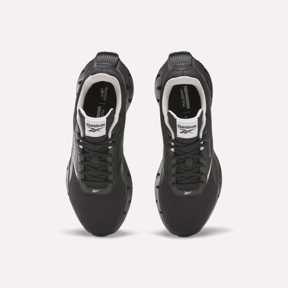 Top view of a pair of black Reebok Zig Dynamica STR Shoes with white accents, black laces, visible logos on the tongues and sides, set on a plain white background—featuring FuelFoam midsoles for enhanced comfort during every run.