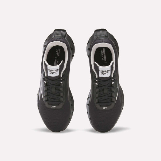 Top view of a pair of black Reebok Zig Dynamica STR Shoes with white accents, black laces, visible logos on the tongues and sides, set on a plain white background—featuring FuelFoam midsoles for enhanced comfort during every run.