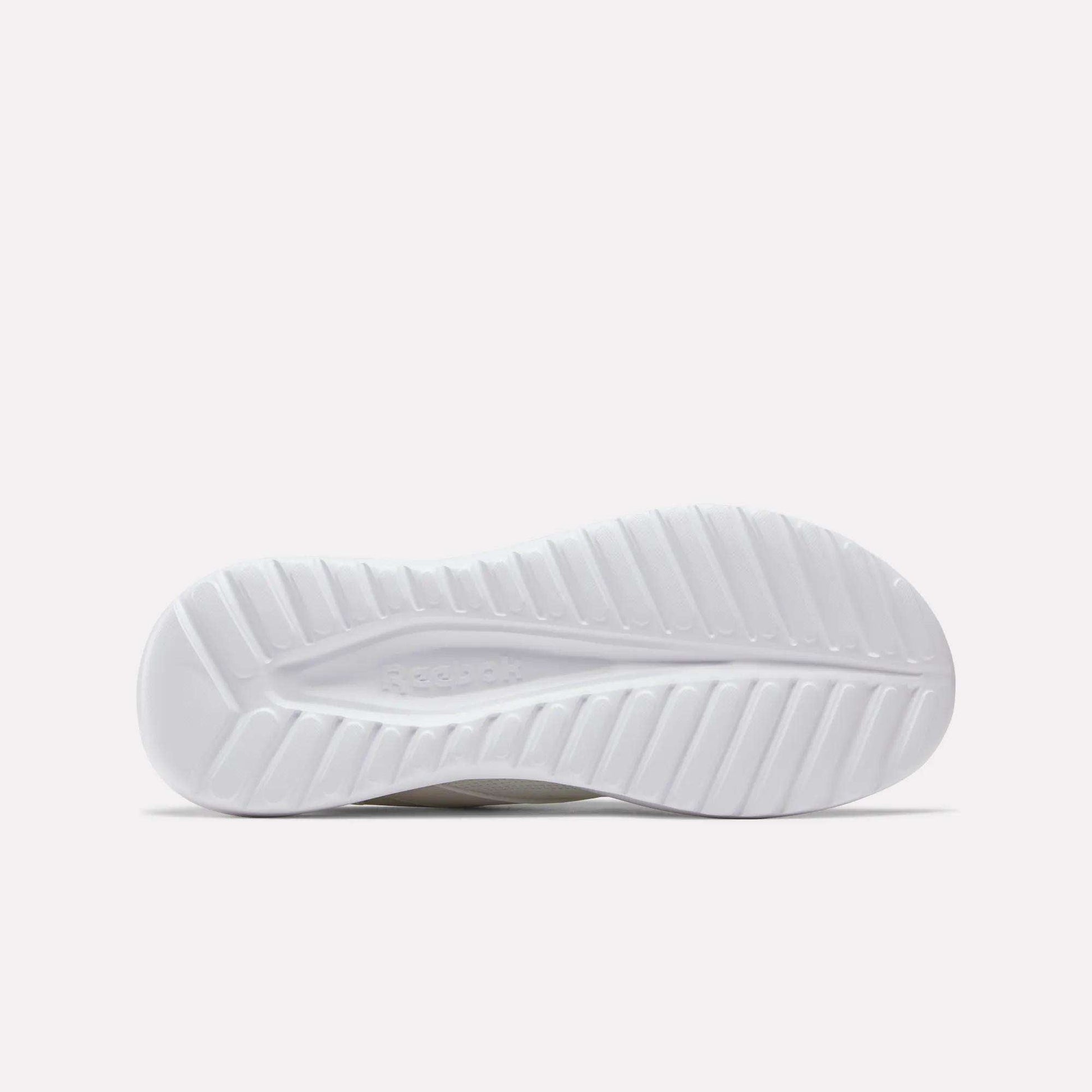 The image displays the white rubber outsole of Reebok Men's Energen Lux Running Shoes, with a wavy, textured pattern for traction. The Reebok logo is subtly featured in the center, set against a plain light background.
