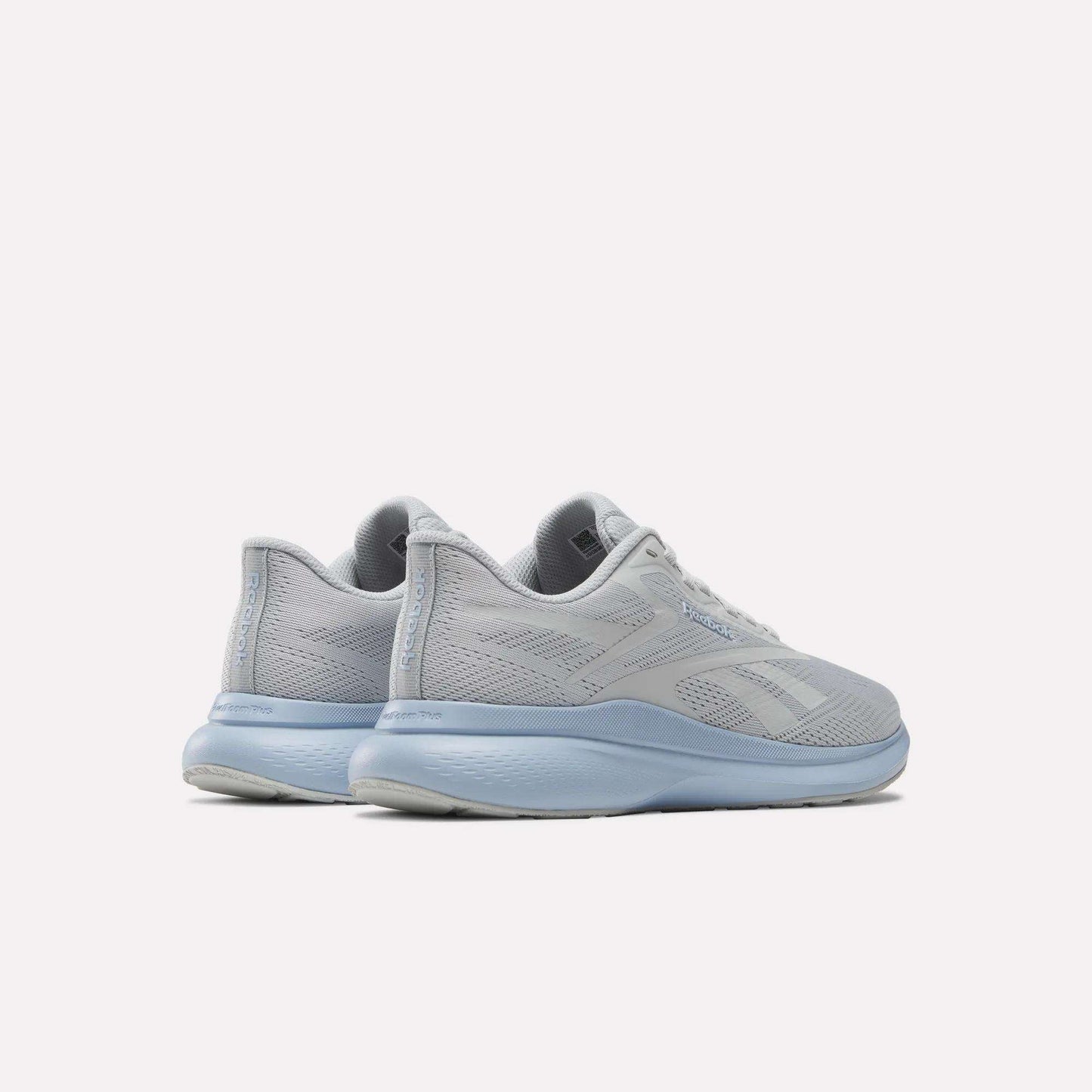 A pair of Women's Energen Run 4 Running Shoes by Reebok in light gray with breathable mesh uppers and light blue soles and laces, shown from the back and side against a white background.