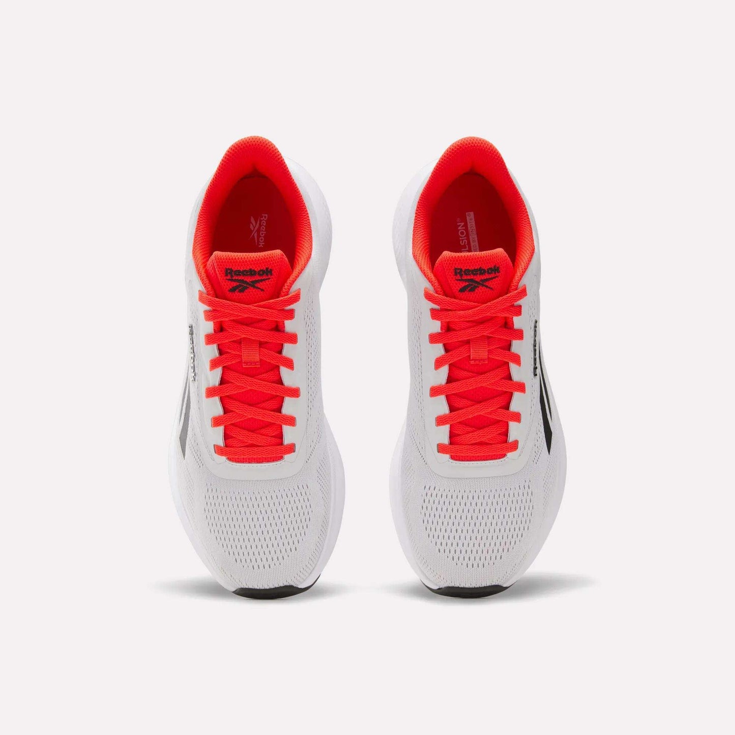 A pair of Reebok Men's Energen Run 4 running shoes in white with black logos, bright red laces, and a breathable mesh upper, viewed from above against a plain light background.