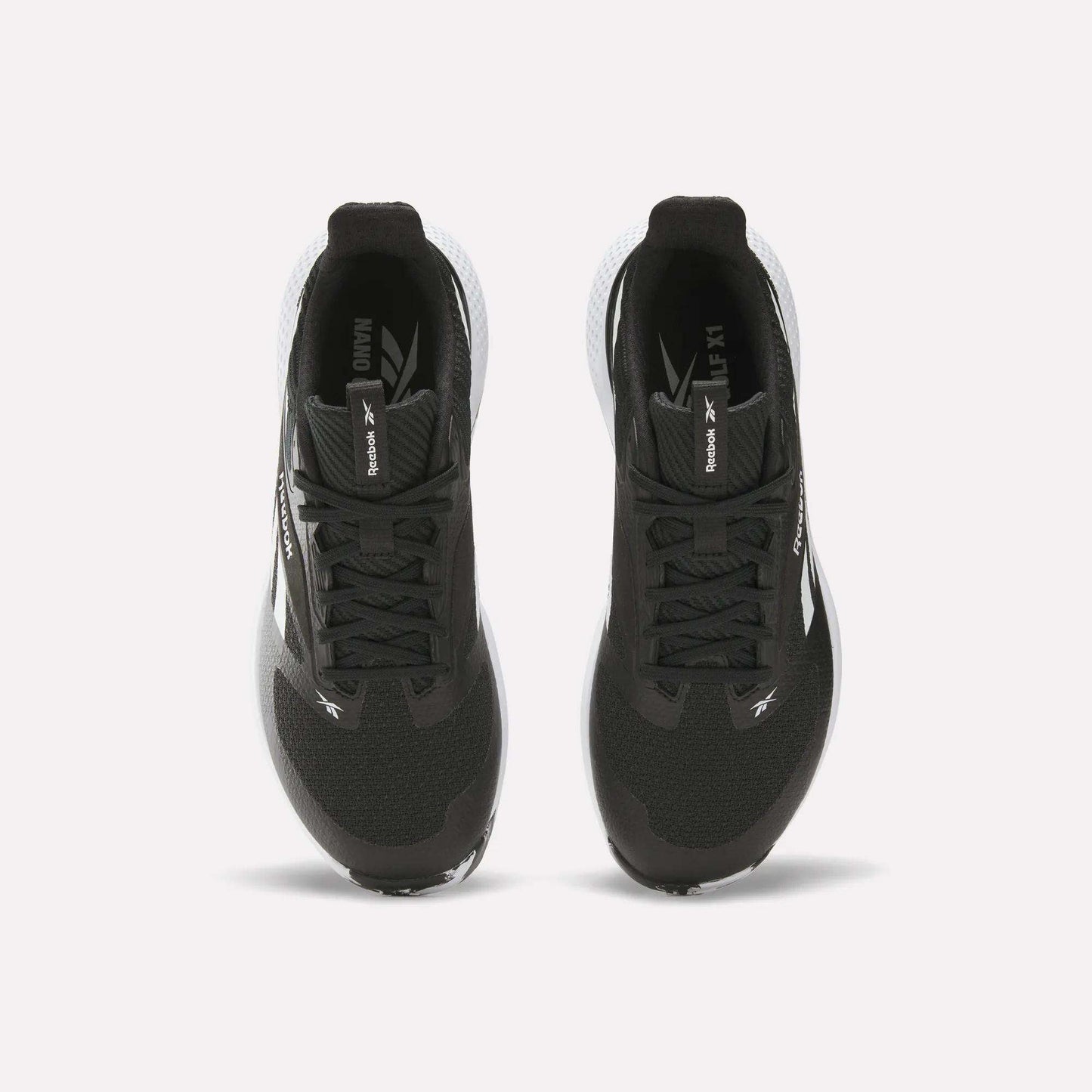 Top view of a pair of black Reebok Nano Golf Shoes with white soles, performance foam cushioning, and Reebok branding on the tongues and sides, positioned side by side on a white background.