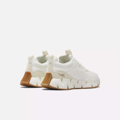 The Reebok Women's Zig Dynamica STR Shoes are white progressive running sneakers with chunky angular soles, FuelFoam midsoles, and tan heel/outsole accents, shown on a plain white background.
