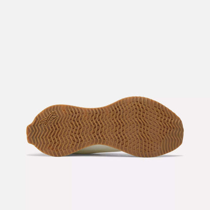 The image features the gum sole of Reebok Women's Zig Dynamica STR Shoes, showcasing a wavy, textured tread and an embossed X logo near the heel, all set against a plain white background.