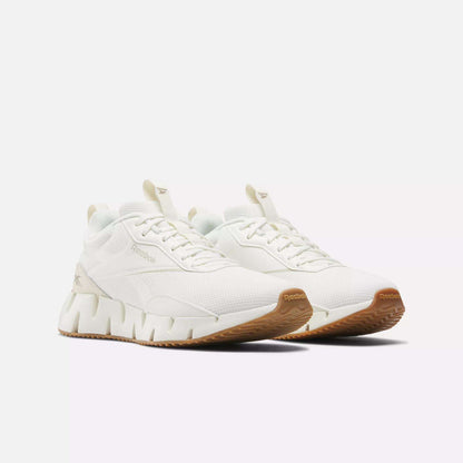 A pair of Reebok Women's Zig Dynamica STR Shoes with a textured sole, gum-colored outsoles, FuelFoam midsole for comfort, and subtle branding on the side and tongue, displayed on a plain white background.