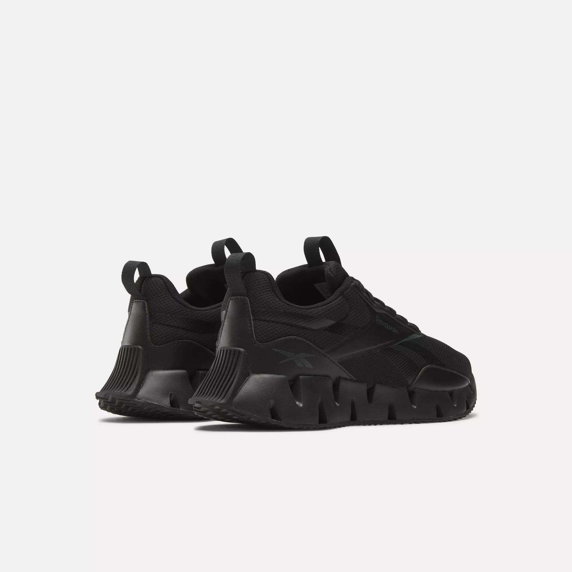 The Reebok Zig Dynamica STR Shoes, shown in black with chunky sculpted soles and heel pull tabs, are angled from the back on a white background—perfect progressive running shoes for both style and support.