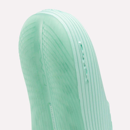 Close-up of the mint green sole of Reebok’s DMX Recovery Walking Slides, featuring textured ridges and embossed DMX text—a reference to the brand’s moving air cushioning technology.