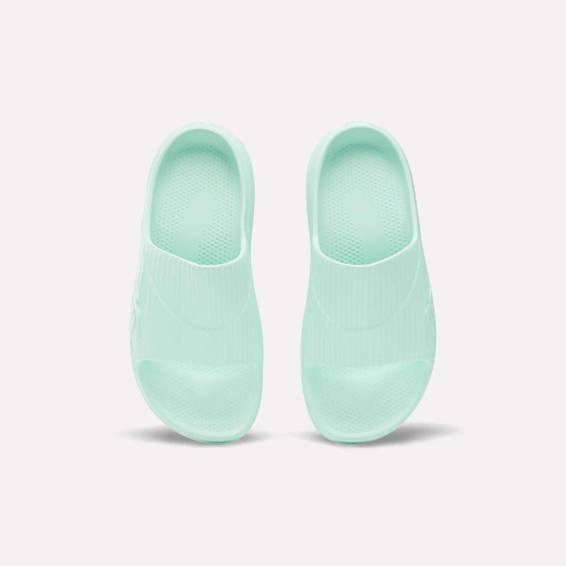 A pair of mint green Reebok DMX Recovery Walking Slides, made with super-soft foam, shown from above on a plain white background.
