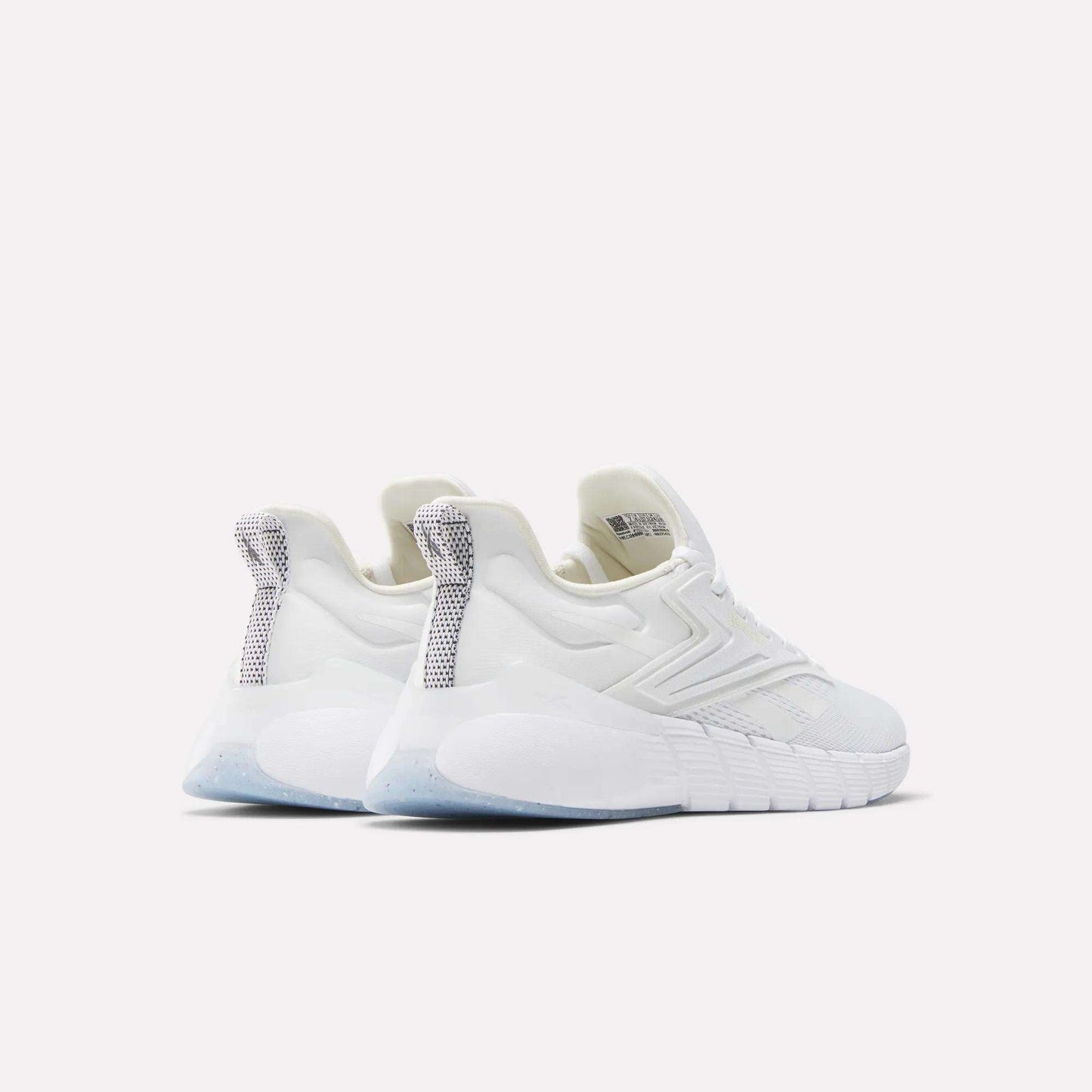 A pair of Women's Nano Gym Training Shoes by Reebok in white, featuring textured soles and silver-gray heel tab accents. Seen from the back, the modern sporty design stands out against a plain light background.