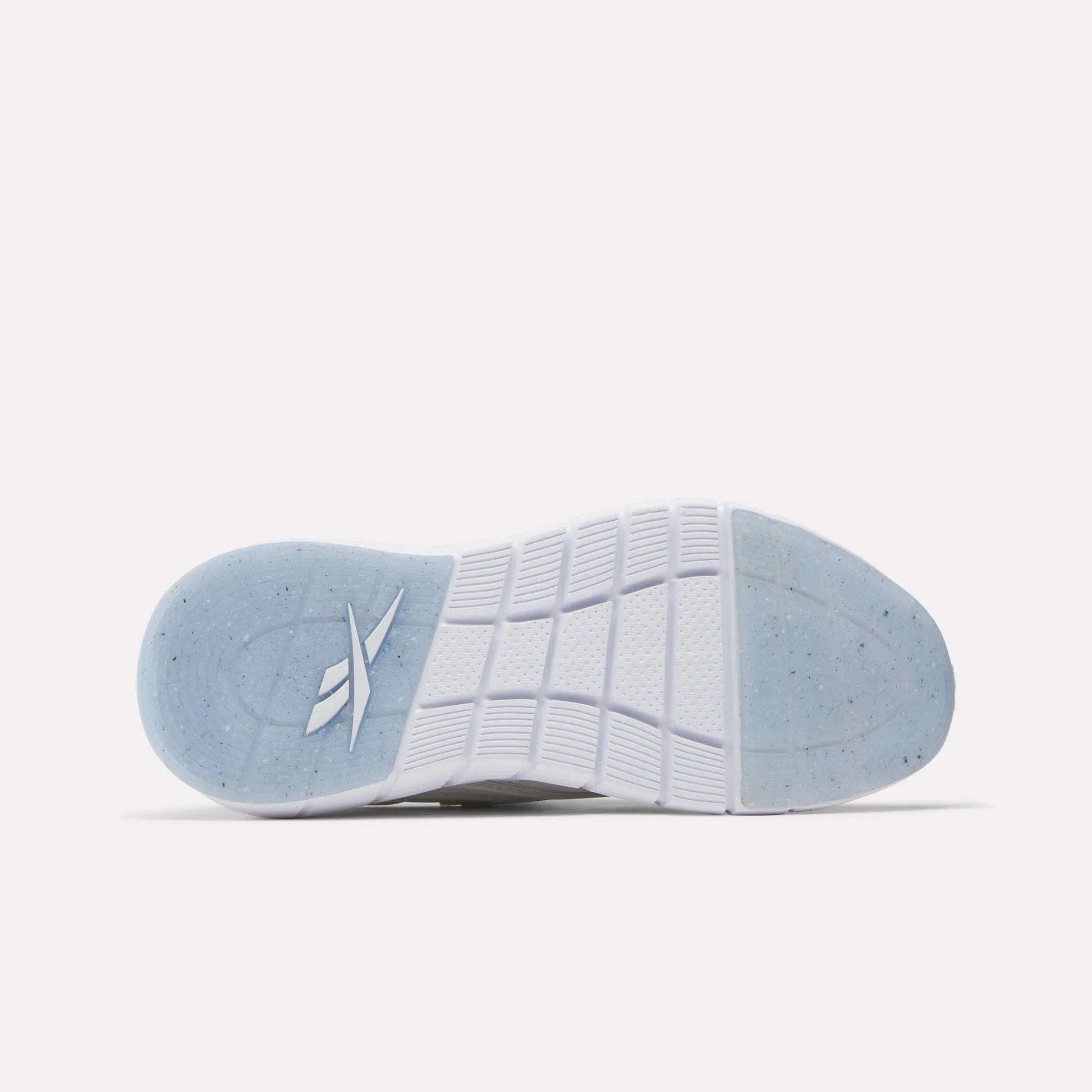 The image shows the bottom view of a white Women's Nano Gym Training Shoe sole by Reebok, featuring a translucent blue heel section with a stylized logo and textured tread for grip—perfect for fitness or cross-training.